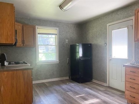 A kitchen with wooden cabinets and a black fridge.