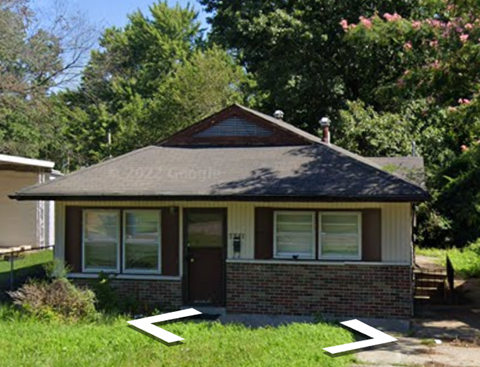 the front of a small brick house with an arrow pointing to the front yard