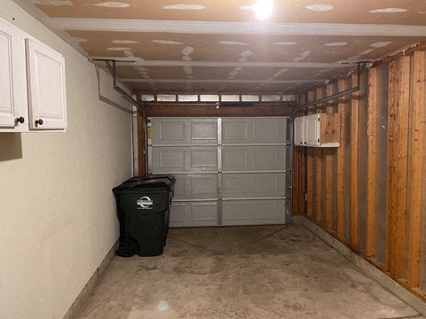 the inside of a garage with a door and a trash can