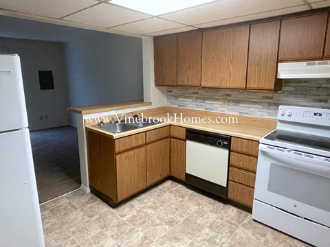 an empty kitchen with white appliances and wooden cabinets