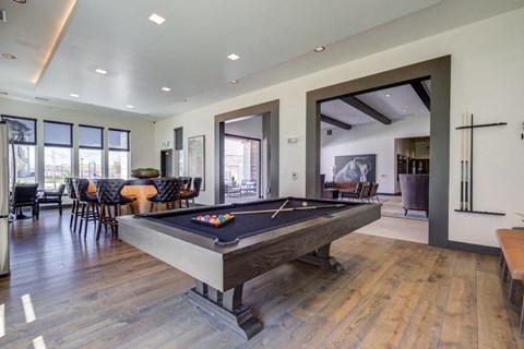 A pool table is in the middle of a room with a wooden floor.
