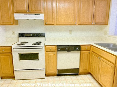A kitchen with wooden cabinets and a stove top oven.