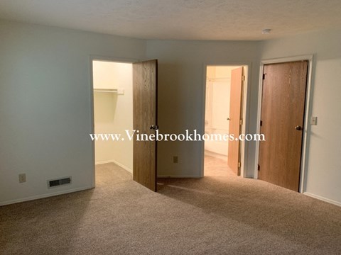 a bedroom with two doors and a closet and a carpeted floor