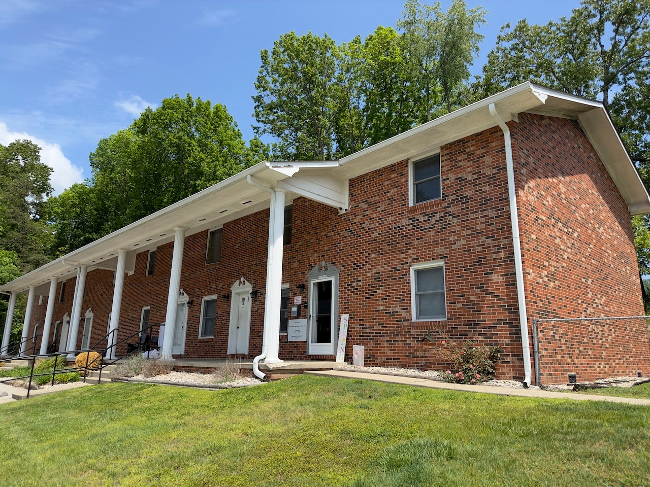 a brick house with white columns and a lawn