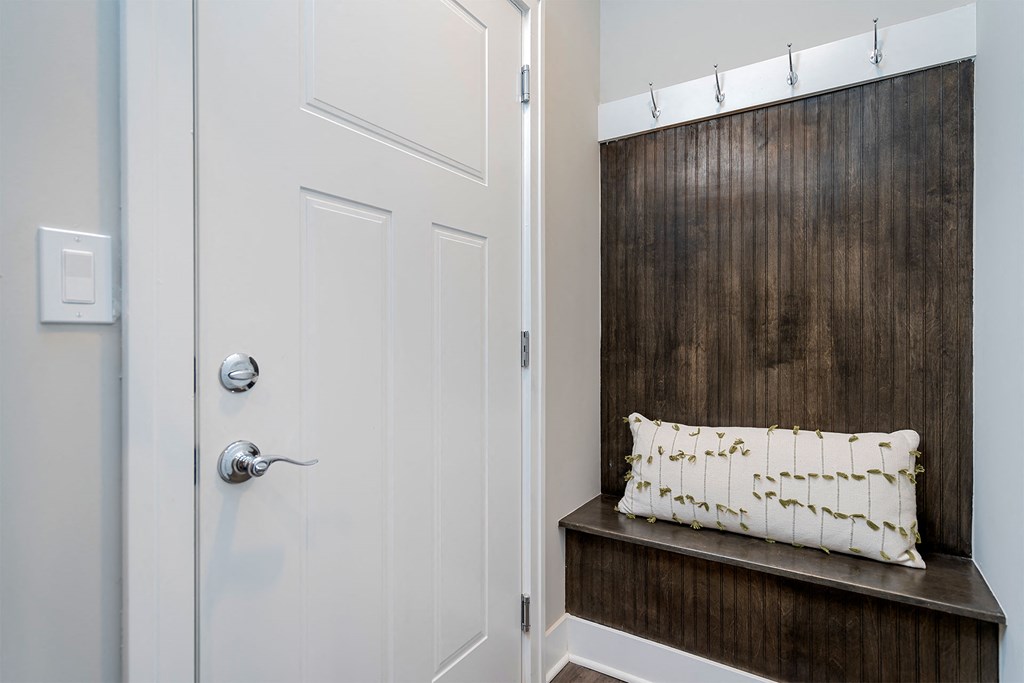 a hallway with a white door and a bench with a pillow