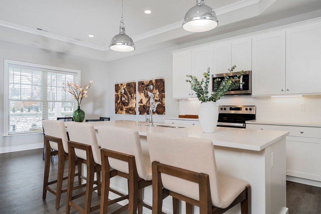 the kitchen has a large island with bar stools and white cabinets