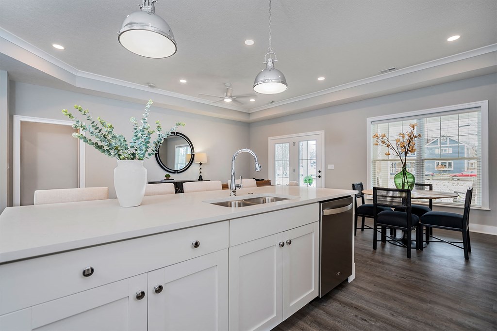 a white kitchen with a sink and a table with chairs