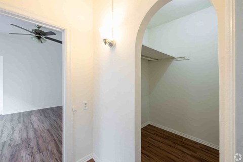 A room with a ceiling fan and a light fixture on the wall.