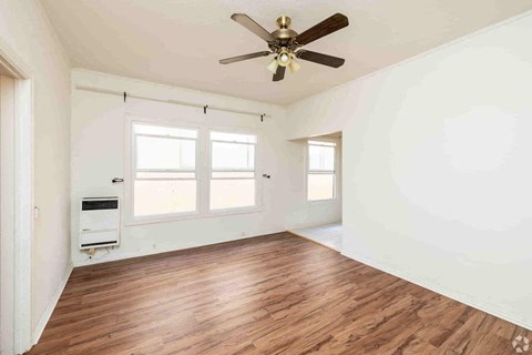 A room with a ceiling fan and wooden flooring.