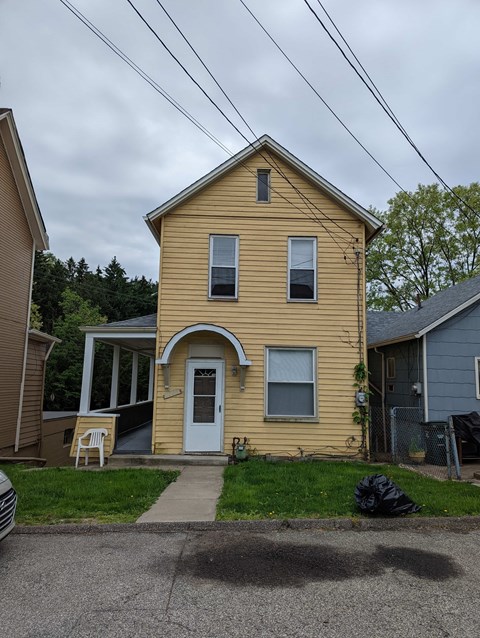 A yellow house with a white door and a small porch.