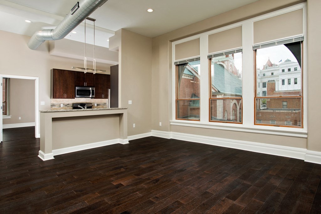 an empty living room with a large window and a kitchen