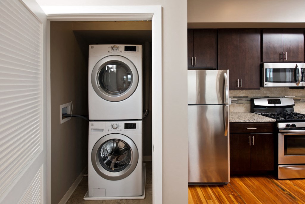 a washer and dryer in a kitchen next to a stainless steel refrigerator