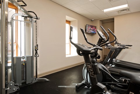 a gym with exercise equipment and a tv on the wall
