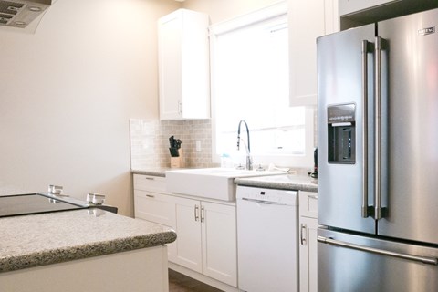 a white kitchen with stainless steel appliances and white cabinets
