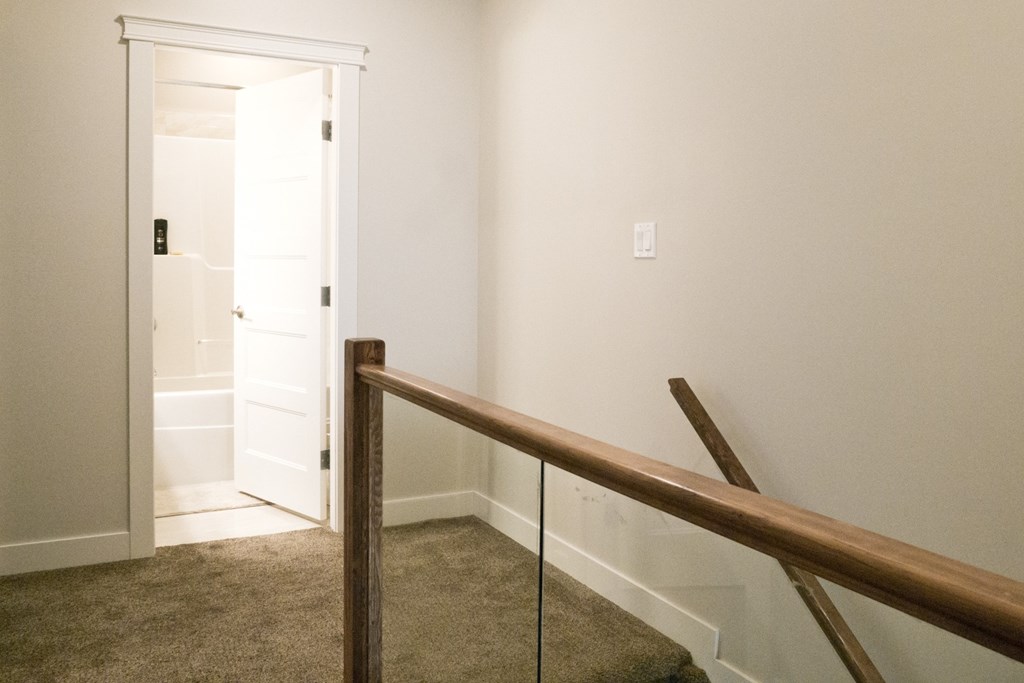 a stairway with a railing and a door to a hallway with a white door