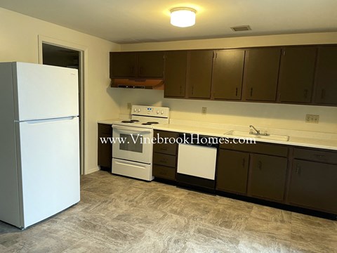 A kitchen with a white fridge, stove, and cabinets.