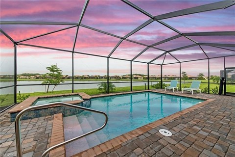 a swimming pool with a view of the water and a pink sky