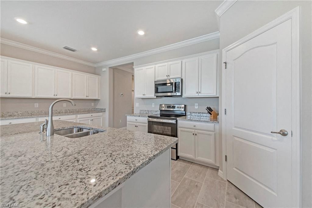 a large kitchen with white cabinets and granite counter tops