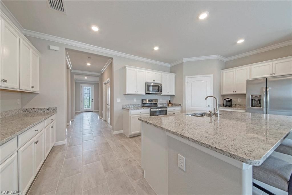 a large kitchen with white cabinets and a marble counter top