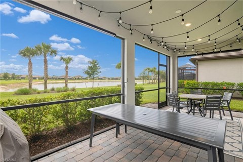a patio with a table and chairs and a view of a lake