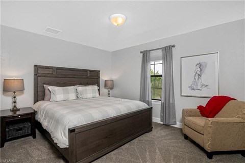 a bedroom with a bed and a chair and a window