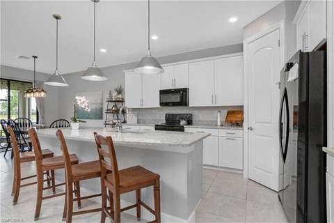 a white kitchen with a large island and chairs