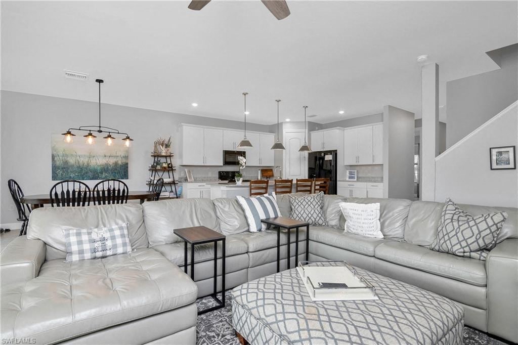 a living room with couches and a table in front of a kitchen