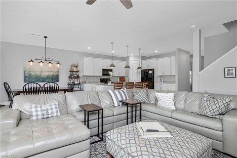 a living room with couches and a table in front of a kitchen