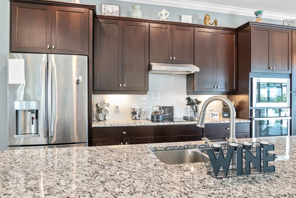 a kitchen with granite counter tops and a stainless steel refrigerator