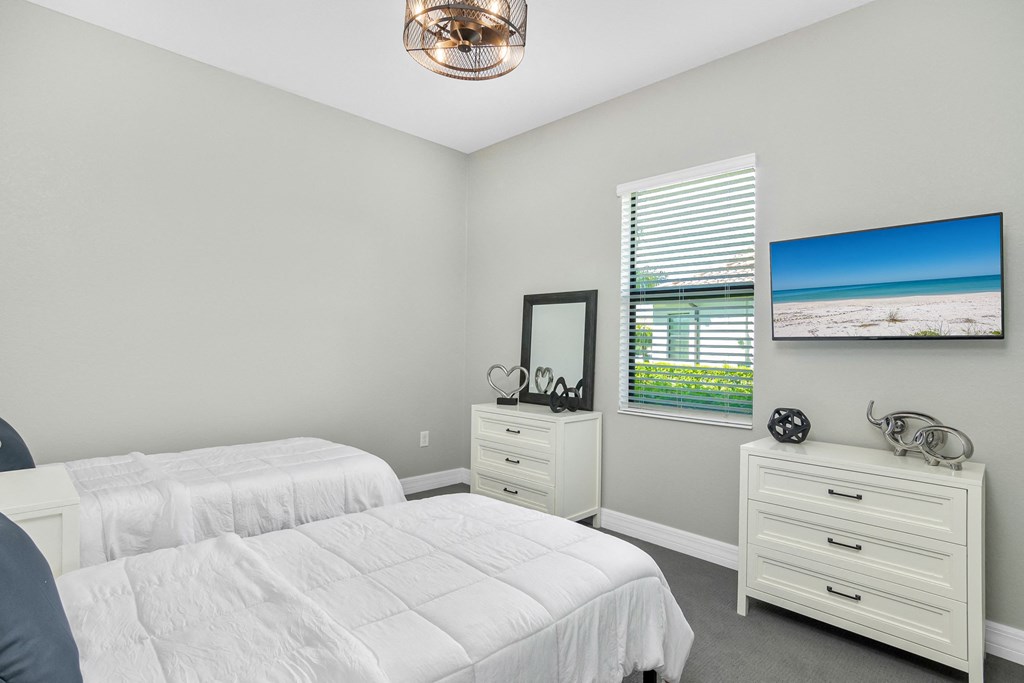 a white bedroom with two beds and a window