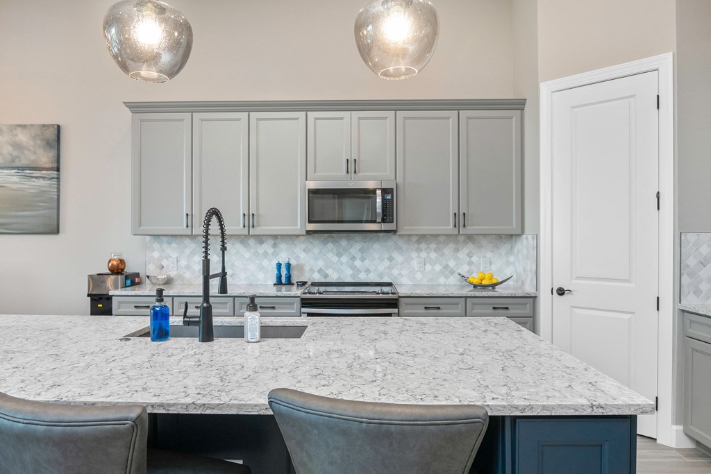 a kitchen with white cabinets and a marble counter top