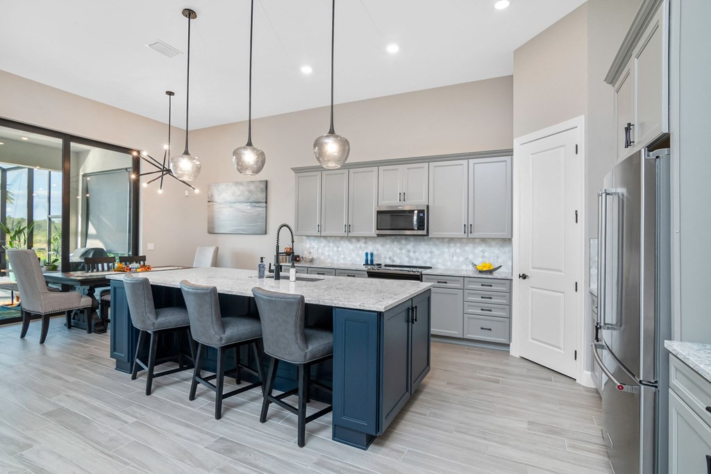 an open kitchen with a large island with blue chairs and a white counter top
