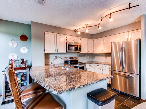 the kitchen has stainless steel appliances and a granite counter top