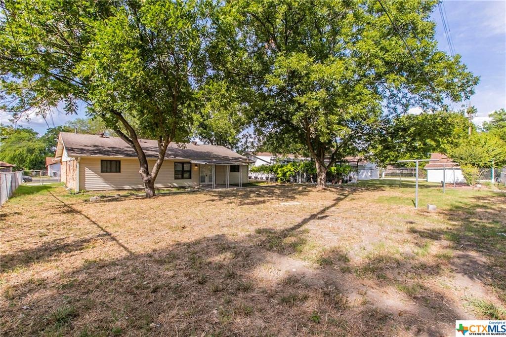 a house with a yard and trees in front of it