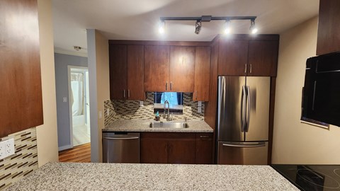 a kitchen with granite counter tops and a stainless steel refrigerator
