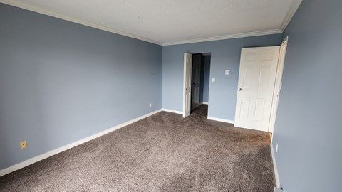 a room with a carpeted floor and a blue wall and a door