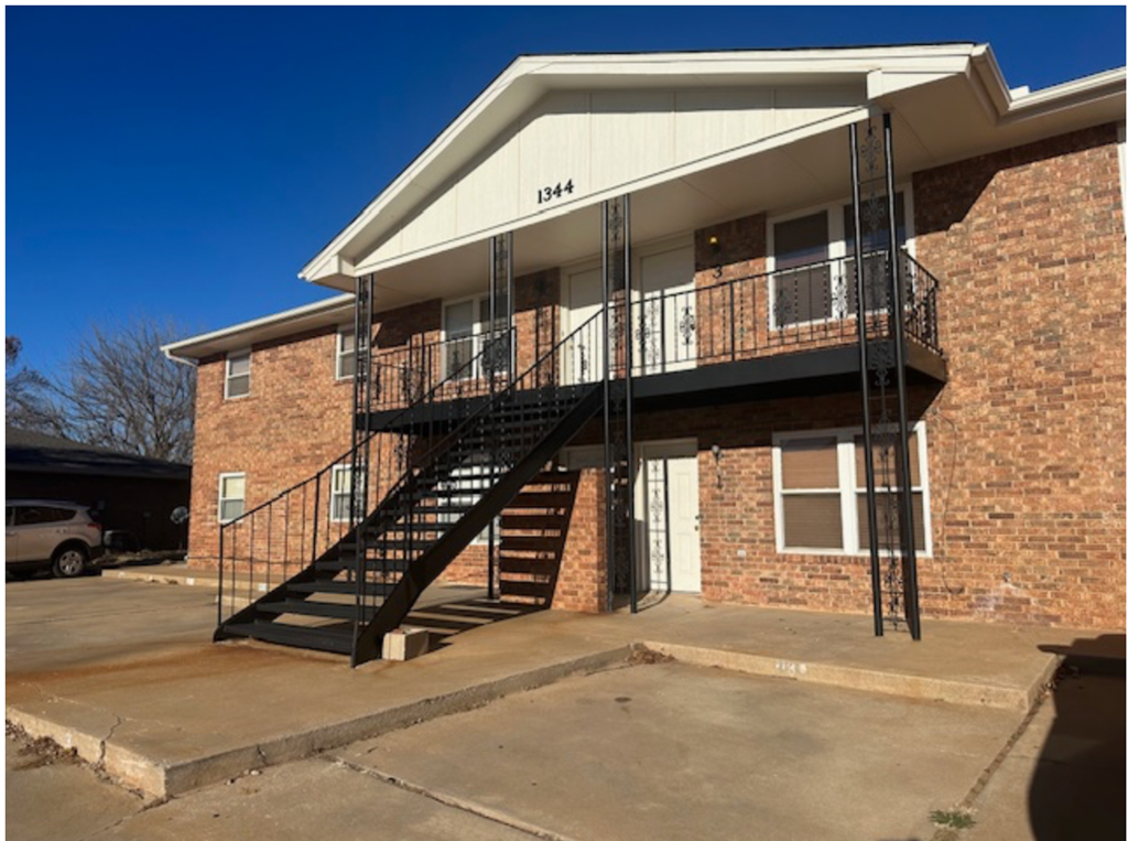 the front of a brick apartment building with a staircase