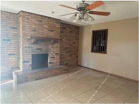 a living room with a brick fireplace and a ceiling fan