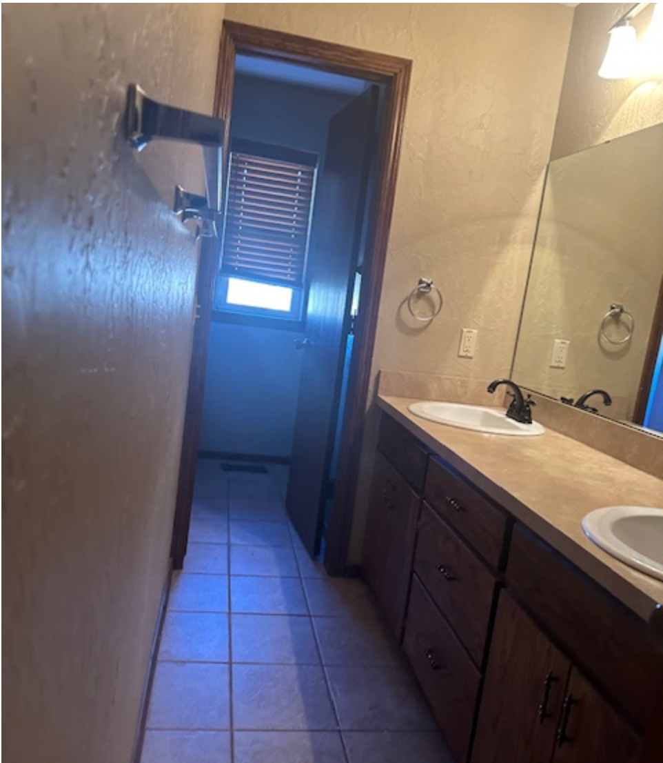 a bathroom with two sinks and a shower and a door