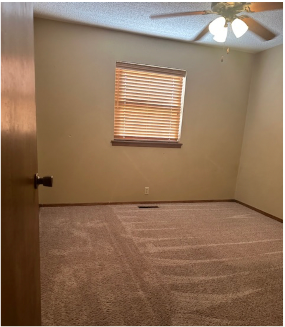 an empty room with a ceiling fan and a window
