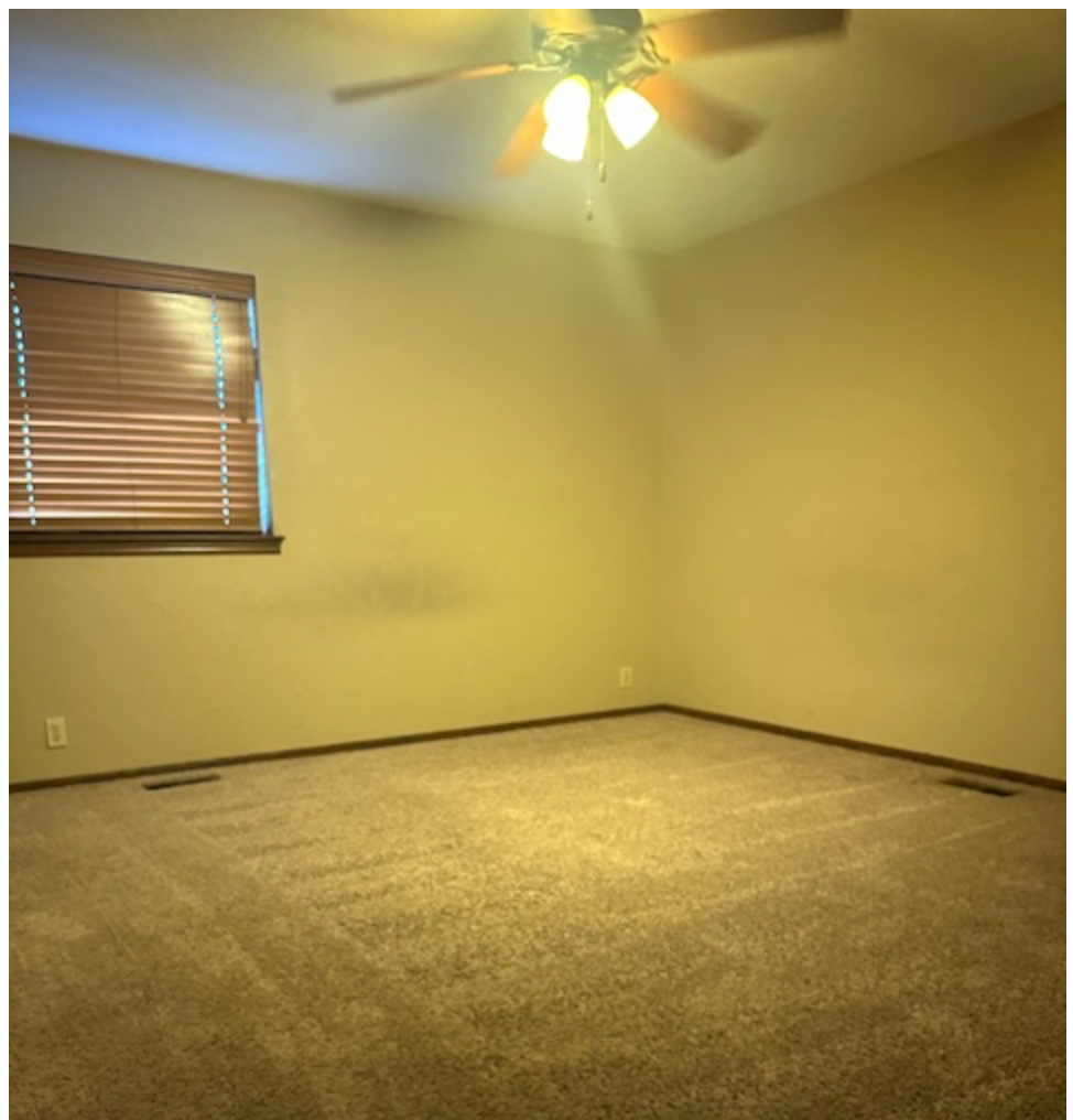 an empty room with a ceiling fan and a window