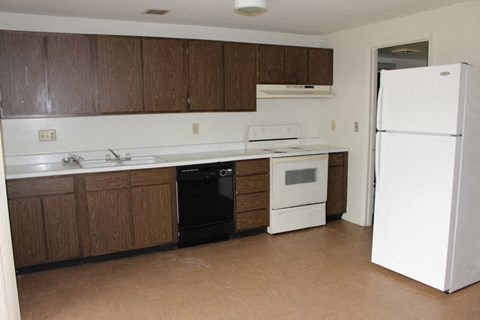 A kitchen with brown cabinets and white appliances.