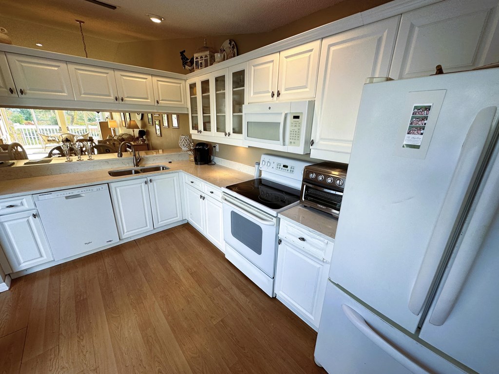 a kitchen with white cabinets and appliances and a refrigerator