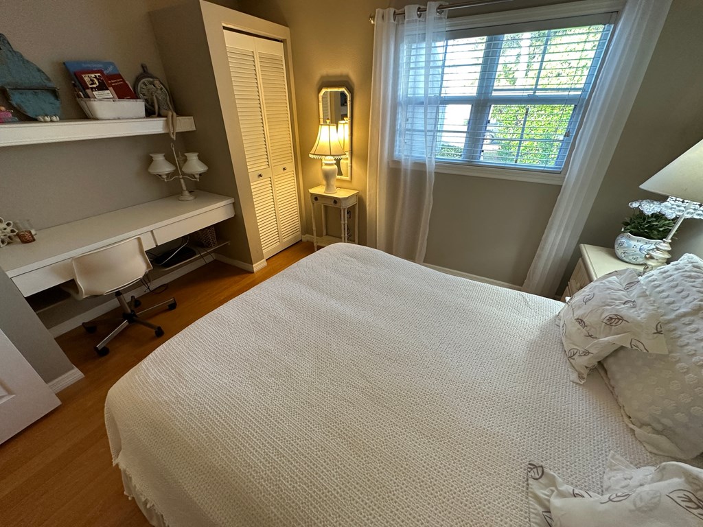 a bedroom with a bed and a desk and a window