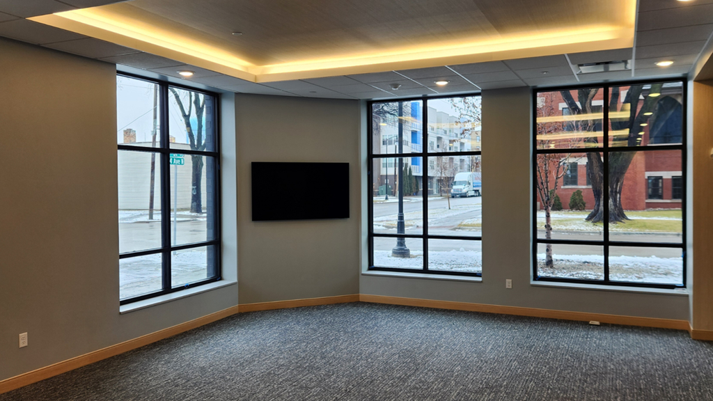 an empty room with large windows and a tv