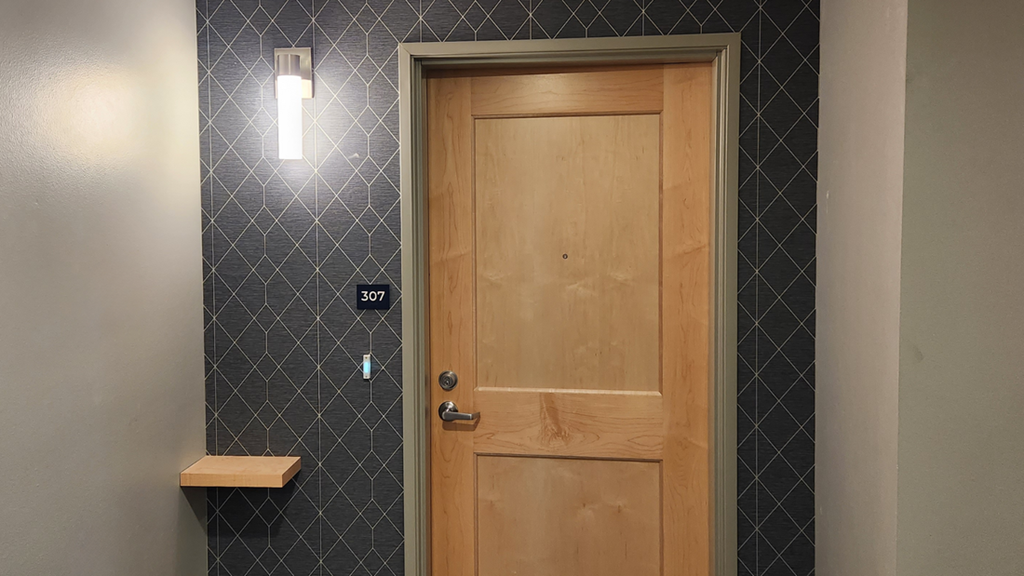 a wooden door in a bathroom with a sink and a mirror