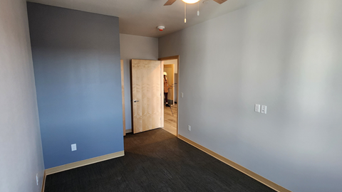 a living room with blue walls and a door to a bathroom