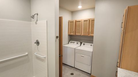 an empty laundry room with white appliances and wood cabinets