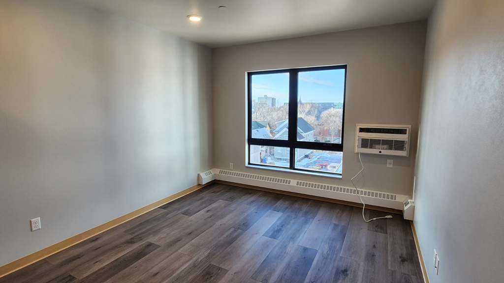 an empty living room with wood floors and a window