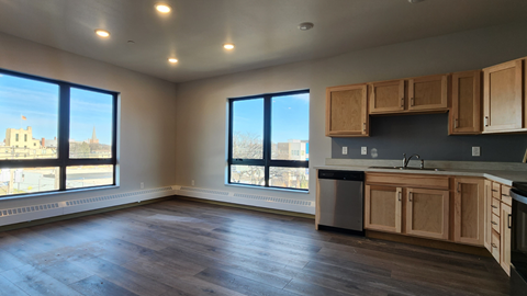 an empty living room with a kitchen and a large window